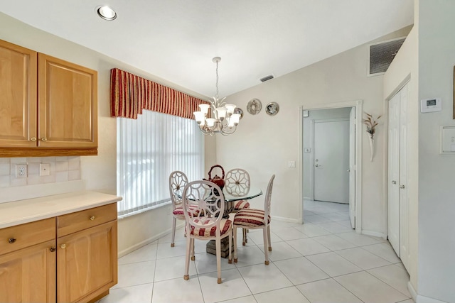 tiled dining room with vaulted ceiling and a notable chandelier