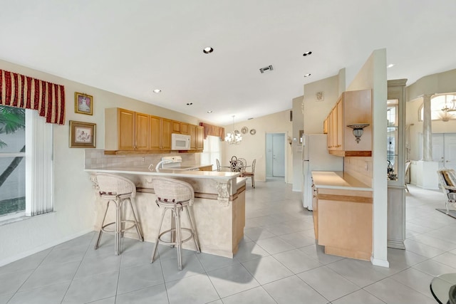 kitchen featuring a breakfast bar, hanging light fixtures, kitchen peninsula, white appliances, and backsplash