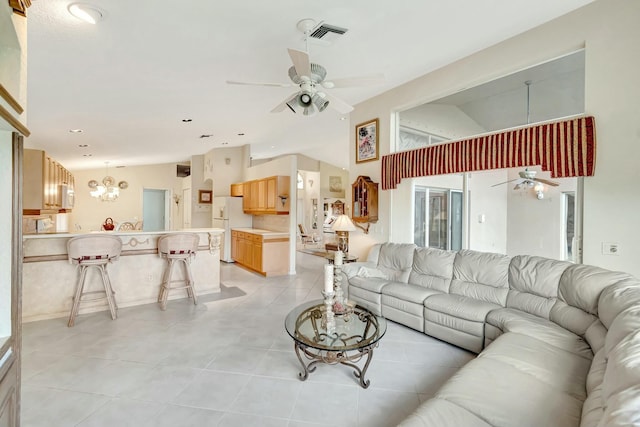 tiled living room with ceiling fan with notable chandelier and vaulted ceiling