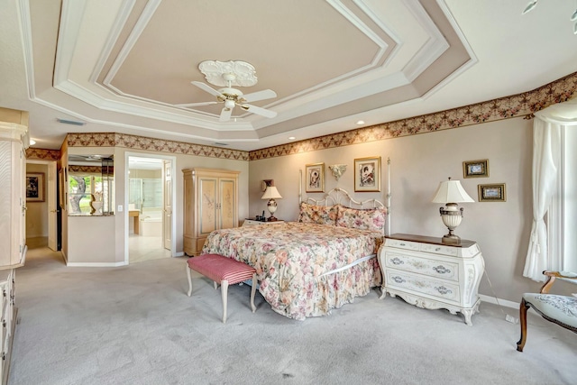 carpeted bedroom with crown molding, ensuite bath, a tray ceiling, and ceiling fan