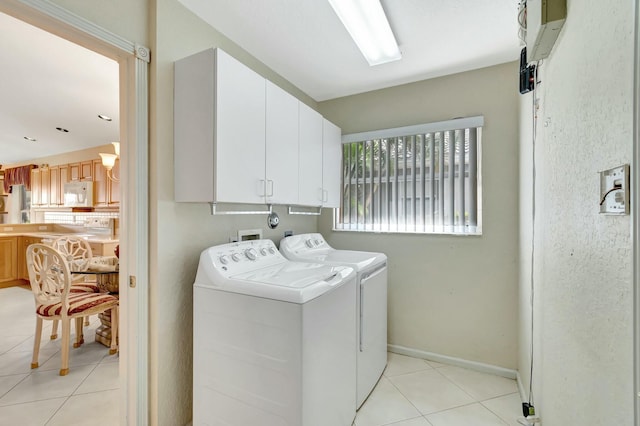 washroom with light tile patterned floors, washer and clothes dryer, and cabinets