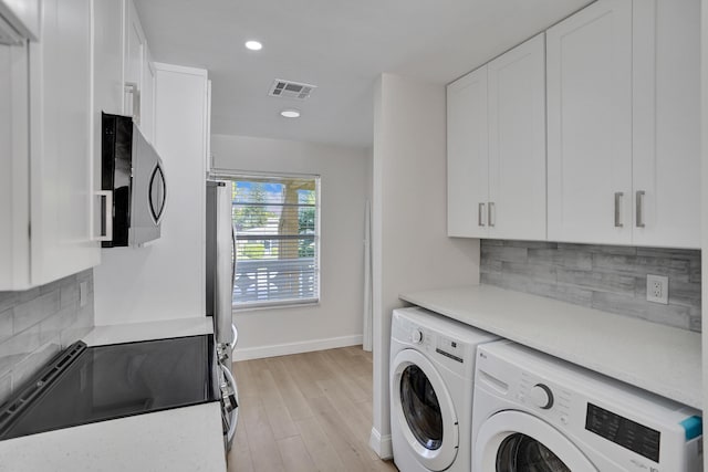 washroom with cabinets, washer and dryer, and light hardwood / wood-style flooring