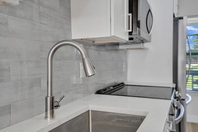 kitchen with a healthy amount of sunlight, white cabinets, light stone counters, and decorative backsplash