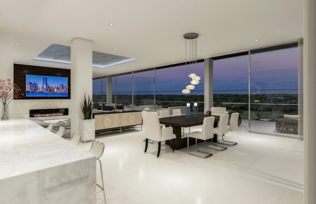 dining area with light floors, a wall of windows, and a glass covered fireplace