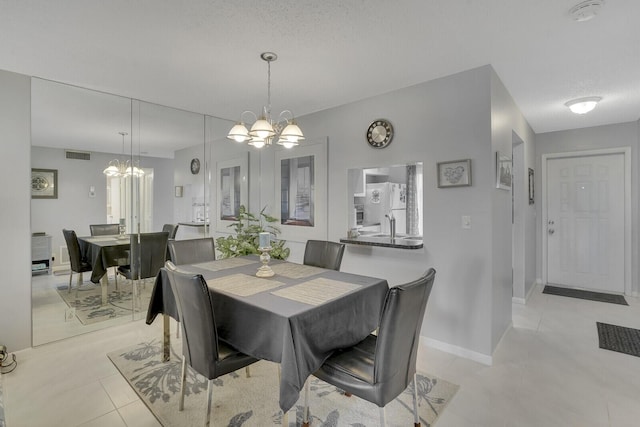 dining room with light tile patterned floors, a textured ceiling, and an inviting chandelier