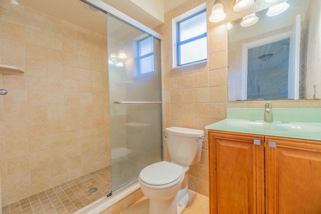 bathroom with vanity, toilet, a shower with shower door, and tile walls