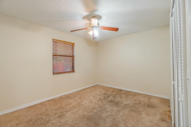 spare room featuring ceiling fan, light carpet, and a textured ceiling