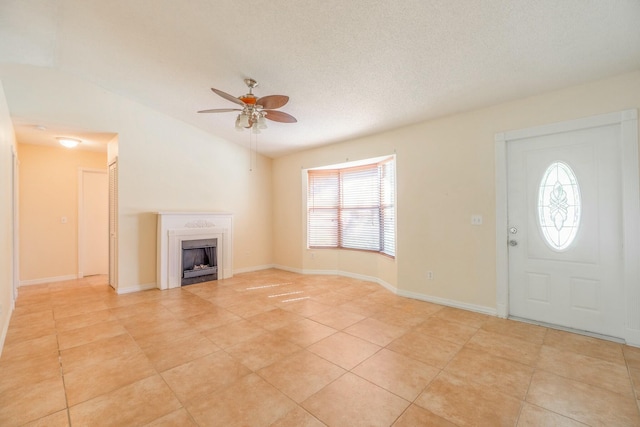 tiled entryway featuring lofted ceiling, a textured ceiling, and ceiling fan