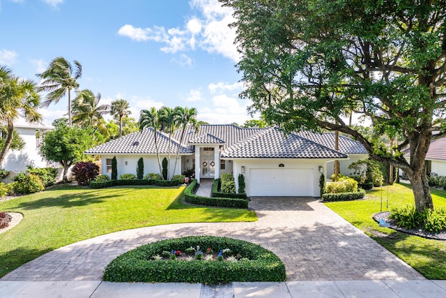 mediterranean / spanish home featuring a garage and a front yard