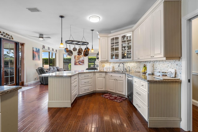 kitchen with sink, stainless steel dishwasher, kitchen peninsula, stone counters, and pendant lighting