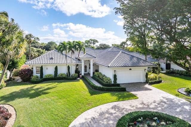 mediterranean / spanish-style house featuring a garage and a front lawn