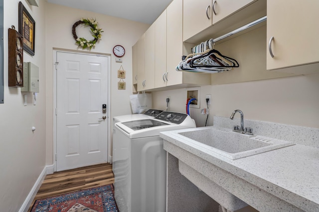 laundry room featuring cabinets, dark hardwood / wood-style floors, sink, and washer and clothes dryer