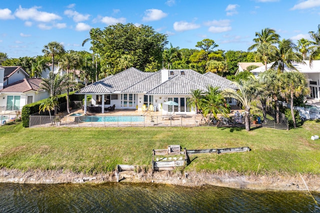 rear view of house featuring a patio area, a lawn, and a water view