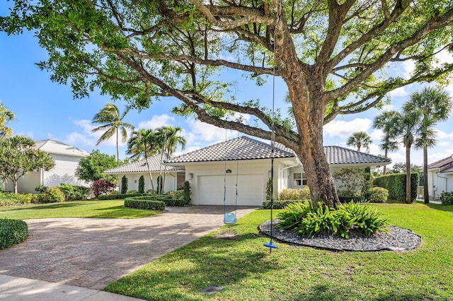 mediterranean / spanish home with a garage and a front lawn