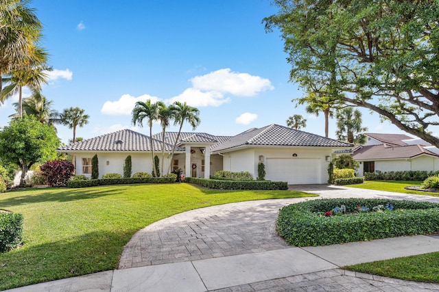 mediterranean / spanish home with a garage and a front lawn