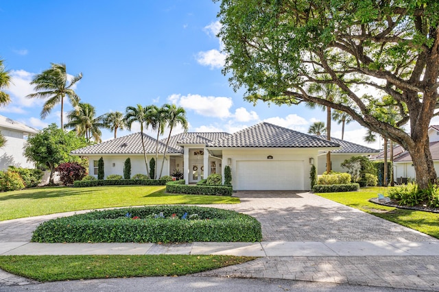 mediterranean / spanish-style home featuring a garage and a front lawn