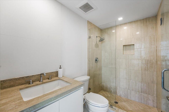 bathroom with vanity, a shower with shower door, and toilet