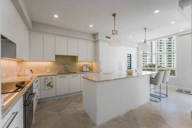 kitchen with sink, white cabinetry, decorative light fixtures, a kitchen island, and black appliances