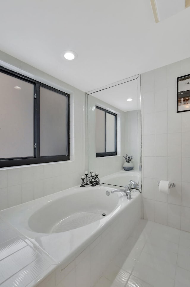 bathroom with tile patterned flooring, tiled bath, and tile walls