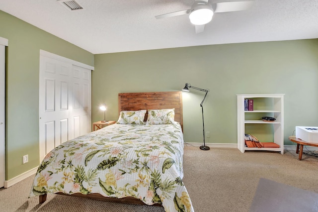 bedroom featuring ceiling fan, light colored carpet, a textured ceiling, and a closet