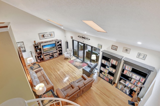 living room with vaulted ceiling, hardwood / wood-style floors, and a textured ceiling