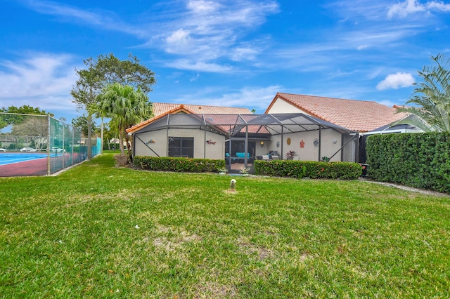 rear view of property featuring a yard and glass enclosure