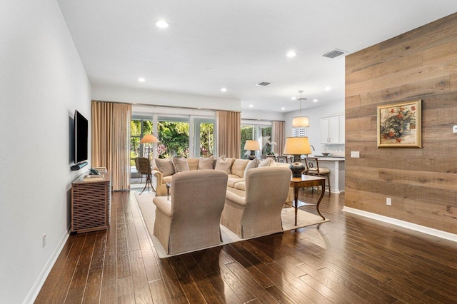 living room featuring dark wood-type flooring and wood walls