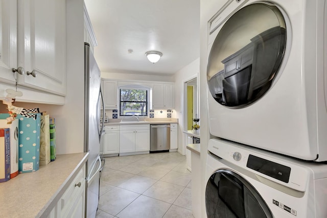 laundry room with sink, light tile patterned floors, and stacked washer and clothes dryer