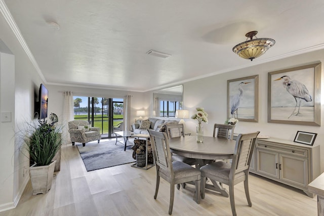 dining room with ornamental molding and light hardwood / wood-style floors