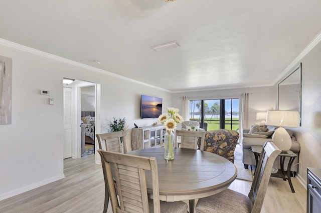 dining room with crown molding and light hardwood / wood-style flooring