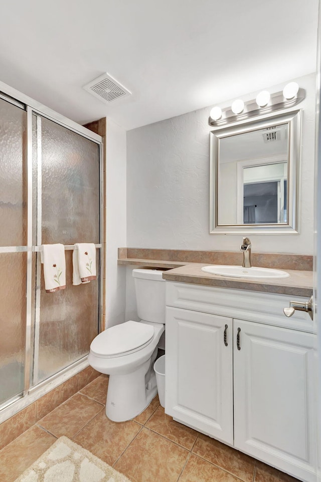 bathroom featuring tile patterned flooring, vanity, toilet, and a shower with shower door