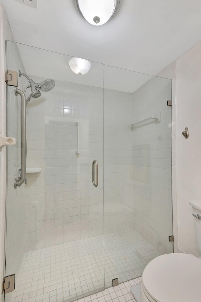 bathroom featuring a shower with door and toilet