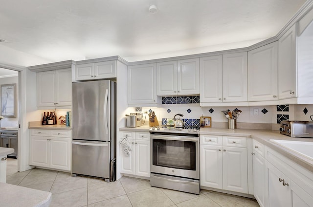 kitchen with tasteful backsplash, white cabinets, and appliances with stainless steel finishes