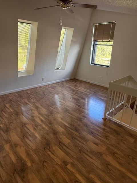 bonus room with a textured ceiling, ceiling fan, lofted ceiling, and dark hardwood / wood-style flooring