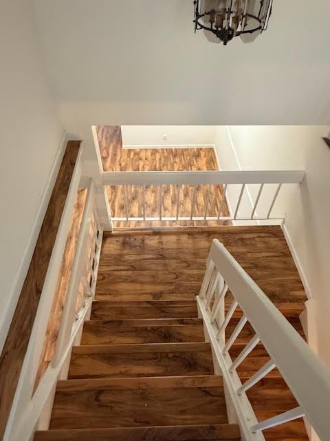 staircase featuring hardwood / wood-style flooring and an inviting chandelier