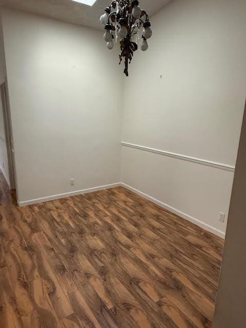 spare room featuring a skylight, a chandelier, and dark hardwood / wood-style floors