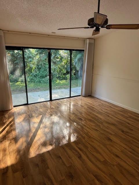 spare room featuring wood-type flooring, a textured ceiling, and a healthy amount of sunlight