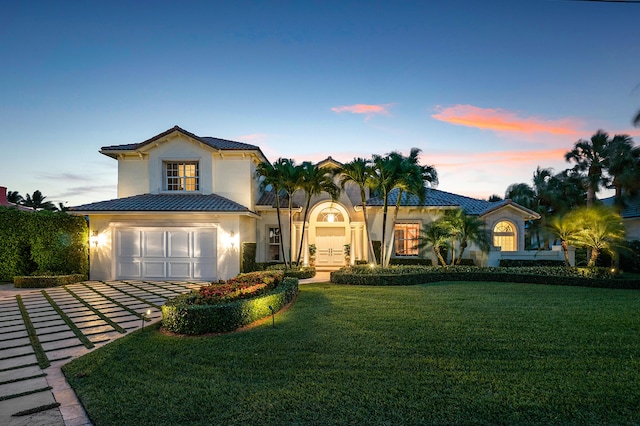 mediterranean / spanish-style house with a garage and a lawn