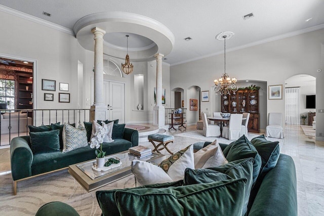 living room featuring a high ceiling, crown molding, a notable chandelier, and ornate columns