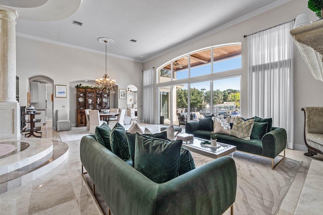 living room with crown molding, an inviting chandelier, a towering ceiling, decorative columns, and a textured ceiling