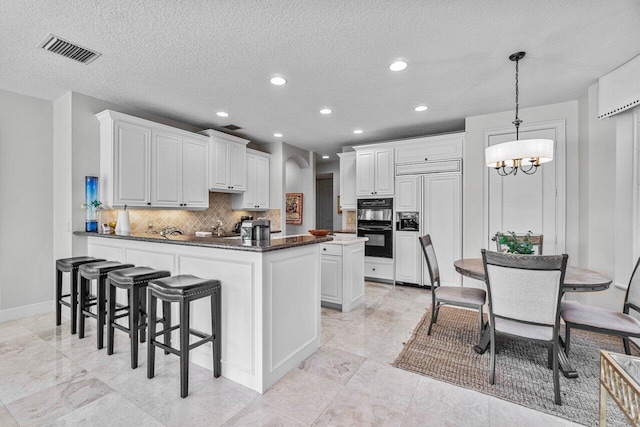 kitchen with decorative light fixtures, kitchen peninsula, paneled fridge, black double oven, and white cabinets