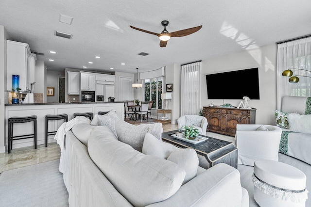 living room featuring ceiling fan and a textured ceiling