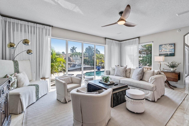 living room featuring plenty of natural light, a textured ceiling, and ceiling fan