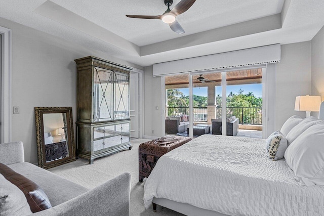 carpeted bedroom with ceiling fan, a tray ceiling, access to exterior, and a textured ceiling