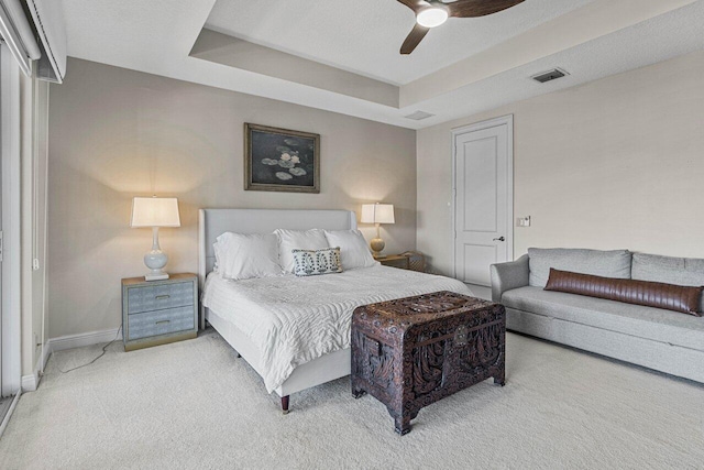 carpeted bedroom featuring a raised ceiling and ceiling fan