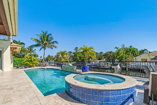 view of pool with an in ground hot tub, a water view, and a patio