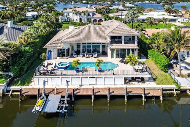 back of house featuring a swimming pool with hot tub, a patio, and a water view