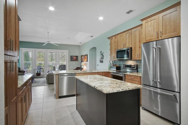 kitchen with sink, appliances with stainless steel finishes, tasteful backsplash, light tile patterned flooring, and kitchen peninsula