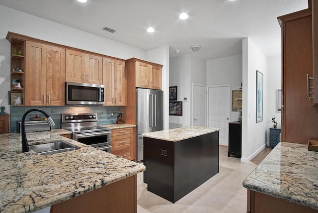 kitchen featuring sink, decorative backsplash, a center island, light stone counters, and stainless steel appliances