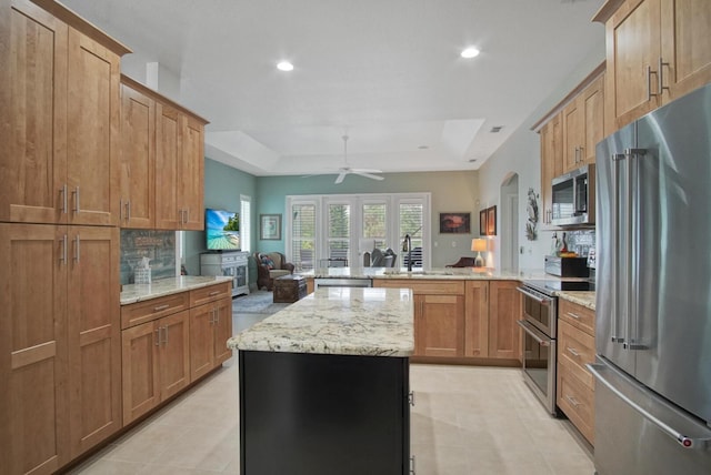 kitchen with sink, stainless steel appliances, a center island, a tray ceiling, and kitchen peninsula